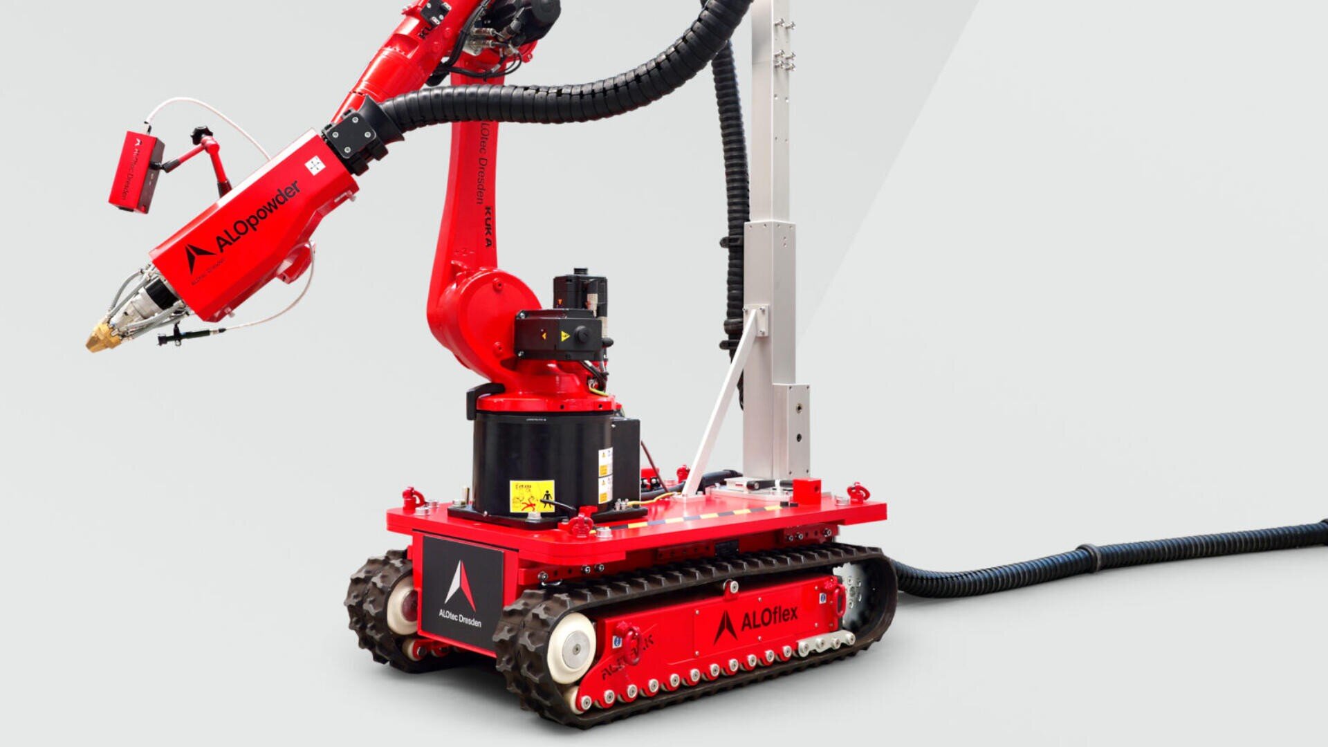 Eine rote, kettenbetriebene Robotermaschine mit einem mechanischen Arm, die für Bau- oder Industrieaufgaben ausgestattet ist und mit dem AI Operator-Branding versehen ist. Die Komponenten sind mit schwarzen Kabeln verbunden.