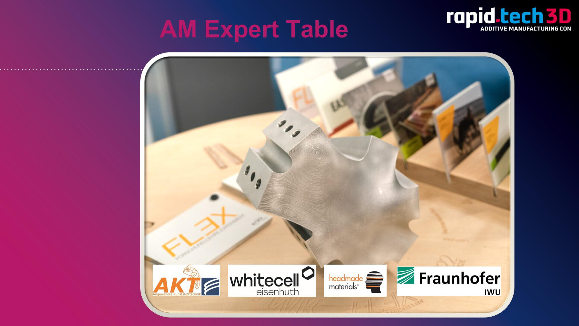 Auf einem Holztisch wird ein metallisches 3D-gedrucktes Objekt präsentiert, umgeben von Informationsbroschüren. Unten sind die Logos von AKT, whitecell eisenhuth, heubach materials und Fraunhofer IWU zu sehen.
