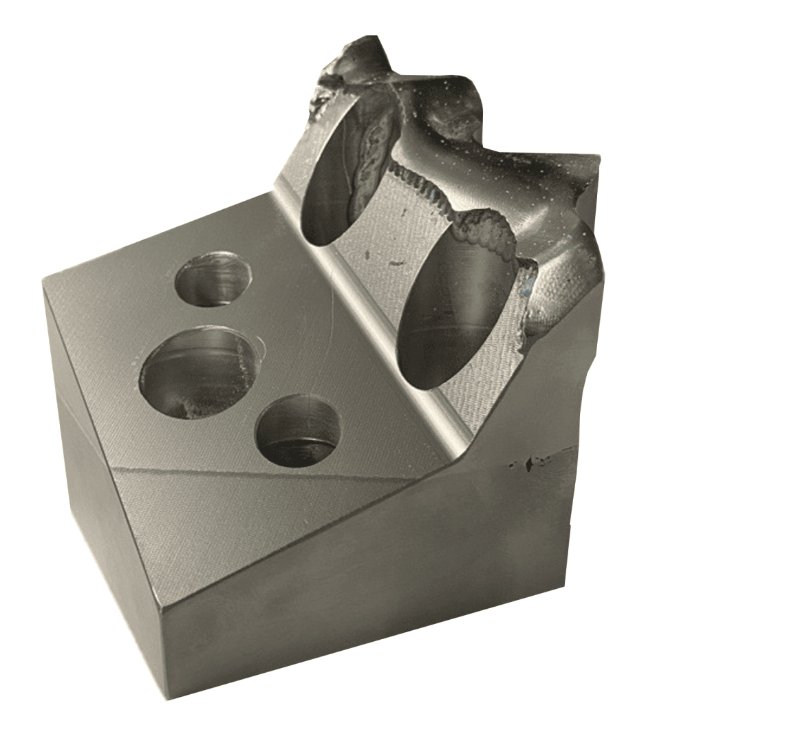 Ein Metallblock mit drei kreisförmigen Löchern, die in eine schräge Fläche gebohrt sind, und einer gezackten, gebrochenen Kante auf der Oberseite, die die raue und unbearbeitete Oberfläche hervorhebt.