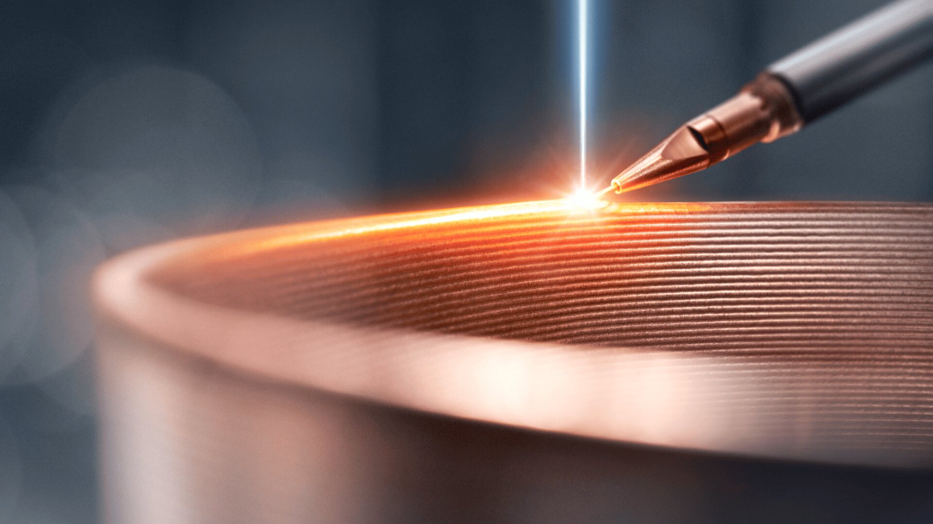 Nahaufnahme eines metallischen Gegenstands mit geriffelten Schichten, der mit einem Laser oder einem Werkzeug mit Metallspitze präzise bearbeitet wird, wobei an der Kontaktstelle ein heller Funke entsteht.