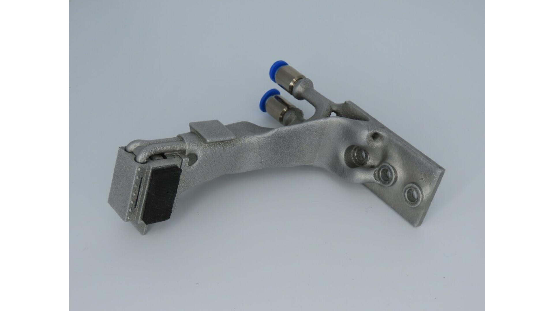 A metallic, L-shaped industrial component with two blue-tipped connectors and several bolts, set against a plain light gray background.