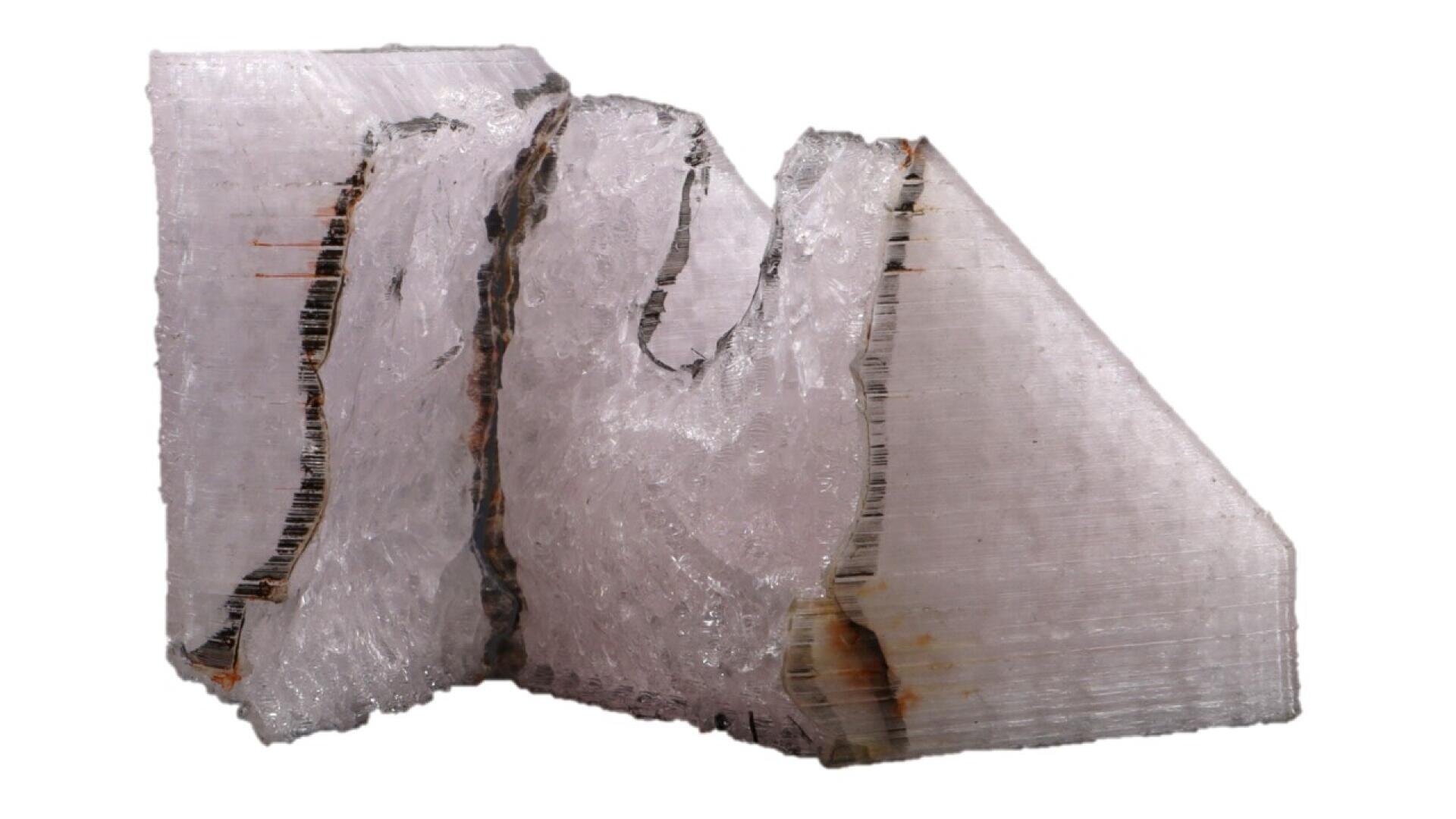 A large, translucent crystal with a pale pink hue, rough and jagged edges, and visible striations on its surface, isolated on a white background.