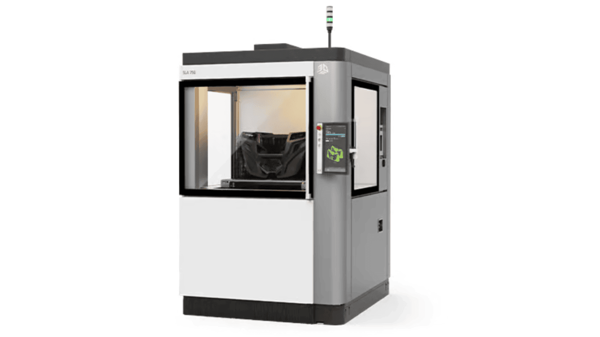 A large, industrial 3D printer with a transparent front panel displays a partially printed black object inside. The machine is grey and white with a digital control panel on the right side and a signal light on top.
