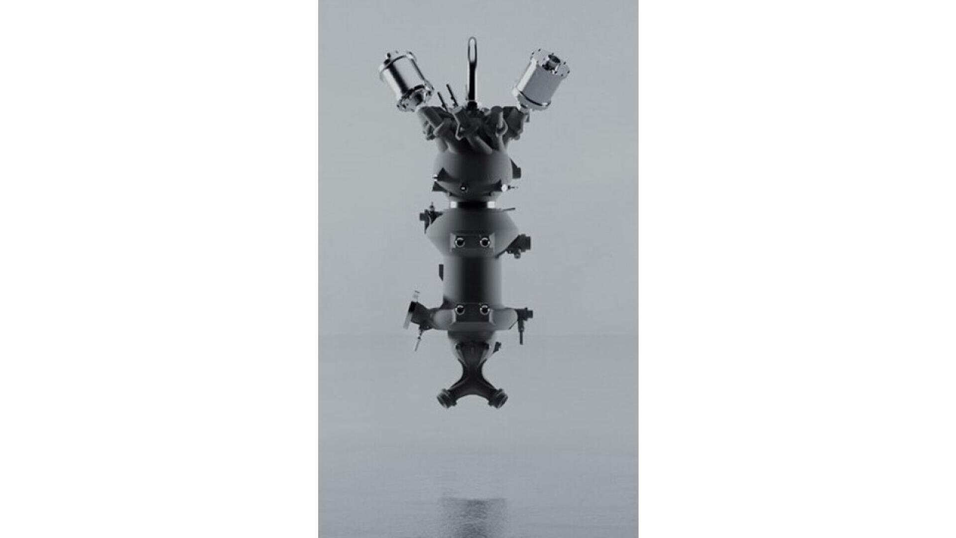 A sleek, metallic, vertical rocket engine stands upright on a reflective surface, featuring multiple cylindrical chambers, valves, and symmetrical thrusters against a plain grey background.
