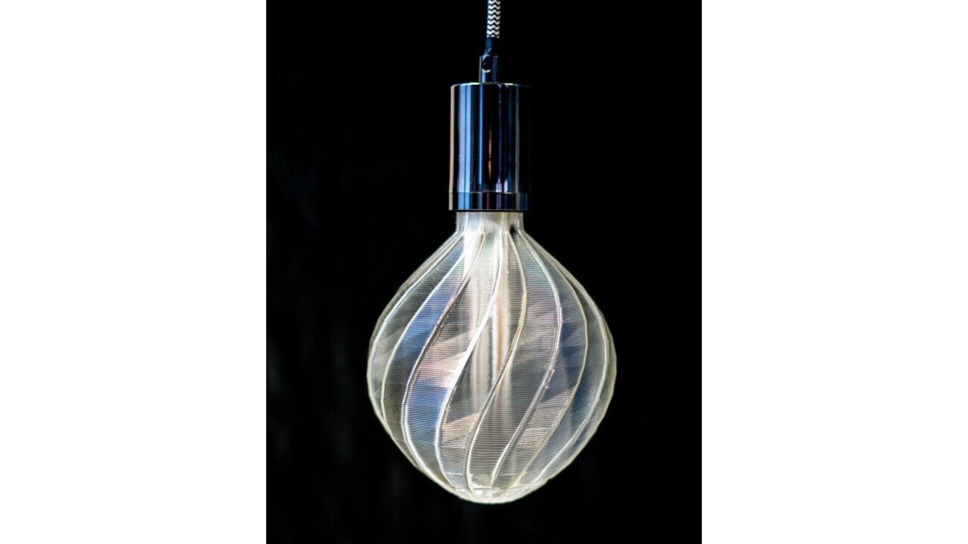 A modern hanging light bulb with a twisted, spiral-patterned glass design and a metallic socket, glowing softly against a black background.