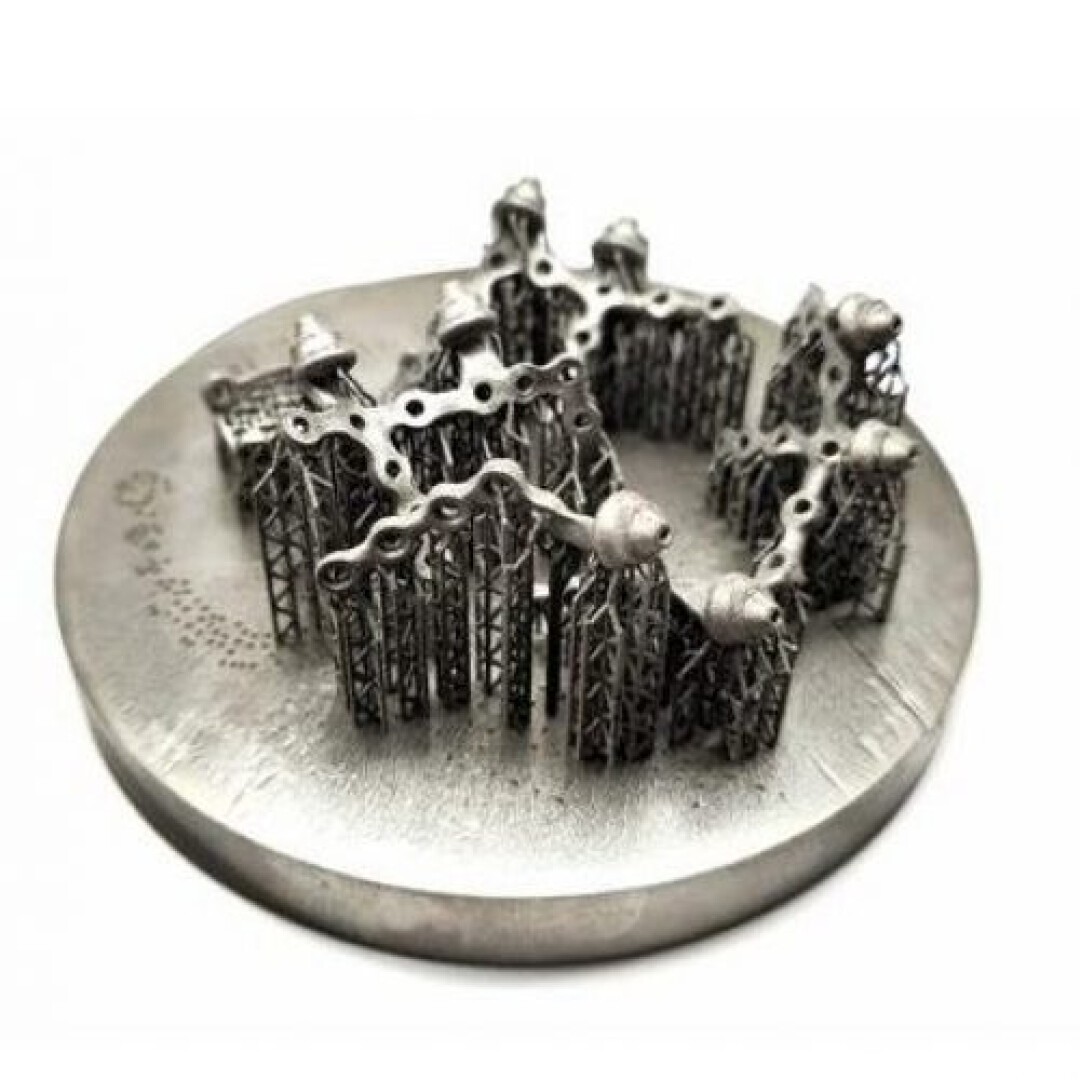 Eine runde Metallscheibe mit komplexen, gitterartigen, 3D-gedruckten Stützstrukturen, die in einem kreisförmigen Muster angeordnet sind und auf deren Oberseite sich einige unregelmäßig geformte Elemente befinden.