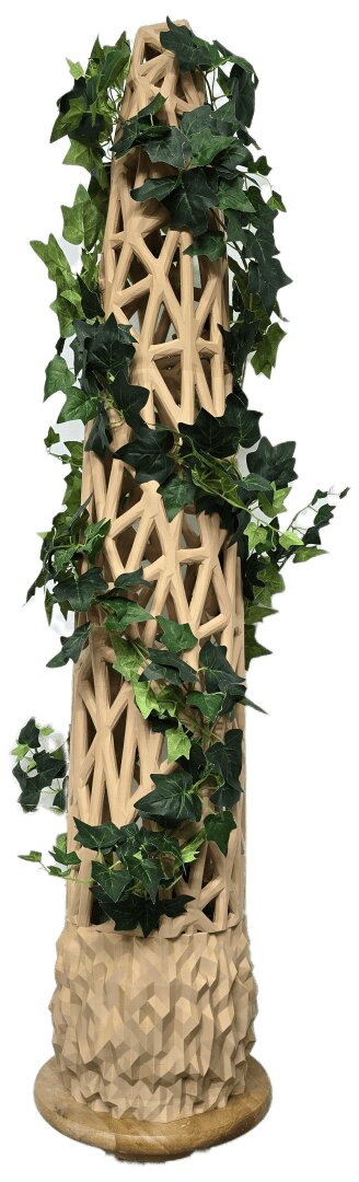 Eine hohe, geometrische Holzskulptur in Form eines Obelisken, um dessen Struktur sich grüne Ranken winden, steht auf einem runden Holzsockel.