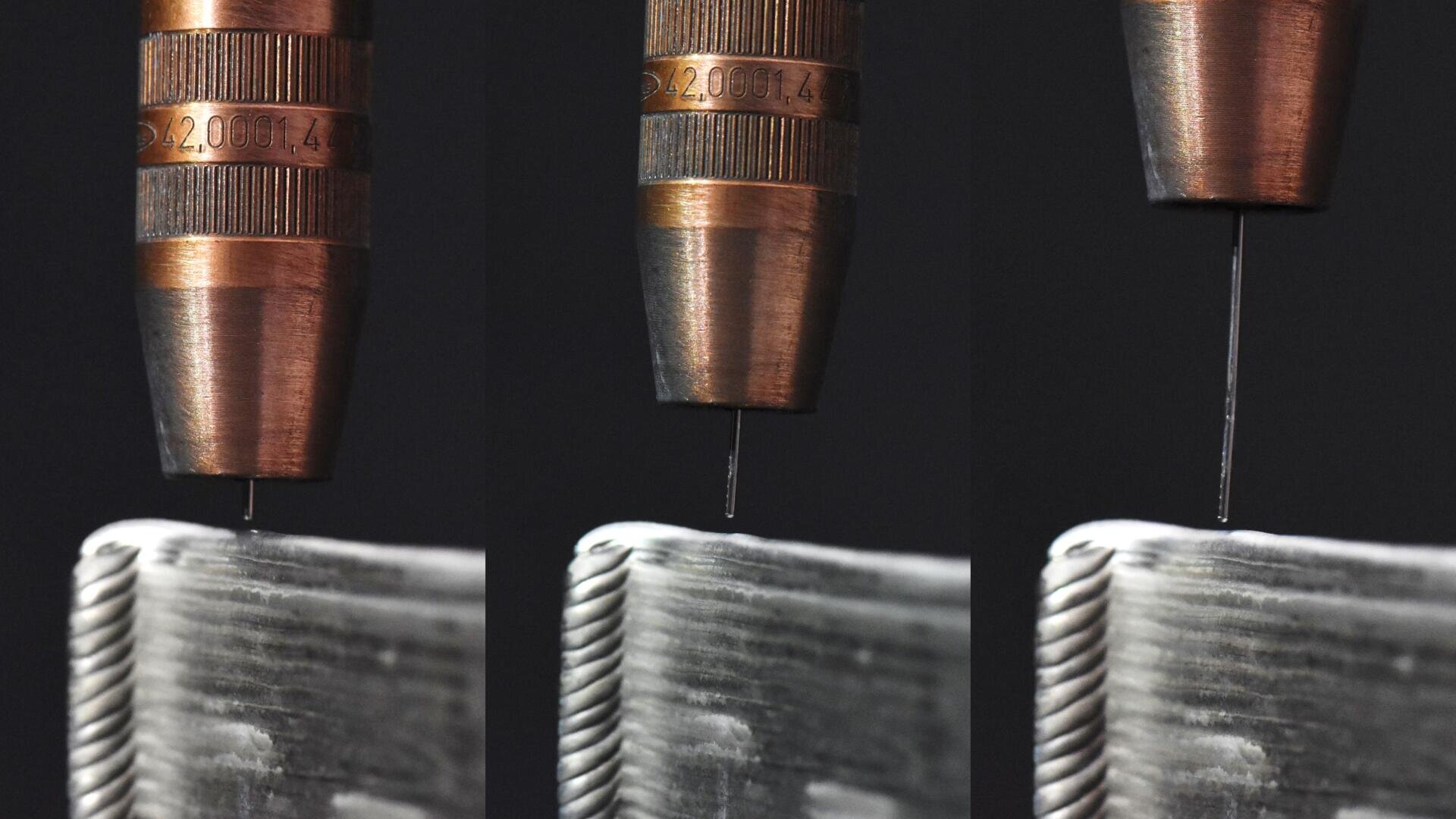 Nahaufnahme von drei Metallspitzen, die jeweils einen dünnen Draht über einer strukturierten metallischen Oberfläche mit einem geflochtenen Rand halten, mit leichten Positionsunterschieden in jedem Feld, vor einem schwarzen Hintergrund.