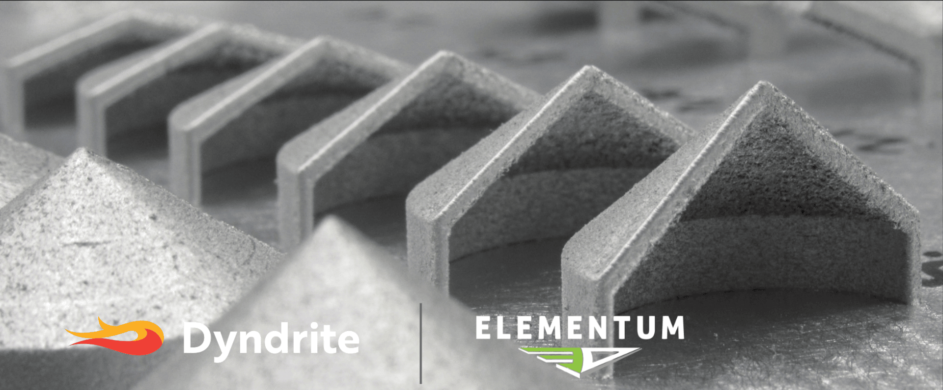 Eine Reihe metallischer, dreieckiger 3D-gedruckter Strukturen ruht auf einer flachen Oberfläche. Die Logos von Dyndrite und Elementum 3D erscheinen am unteren Rand des Bildes.