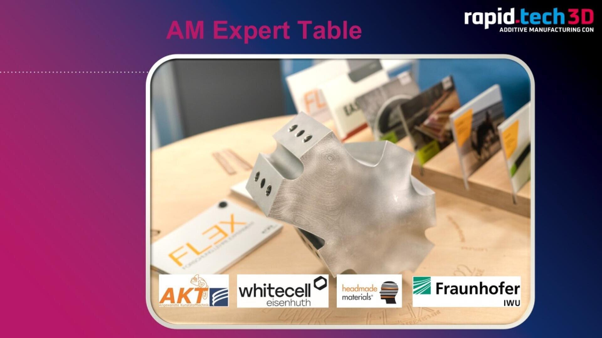 A metallic 3D-printed object is displayed on a wooden table with brochures in the background. Logos of AKT, whitecell eisenhuth, handmade materials, and Fraunhofer IWU are shown at the bottom.
