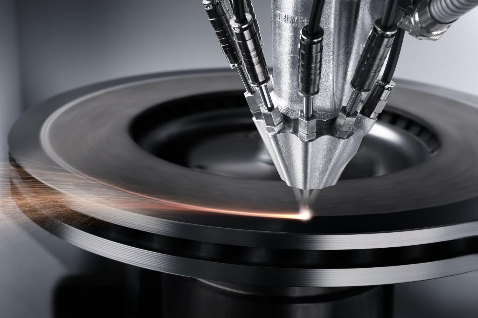 Nahaufnahme einer Laserschneidmaschine in Aktion, die einen fokussierten Strahl auf eine Metallscheibe aussendet, der Funken und einen präzisen Schnitt entlang der Oberfläche erzeugt.