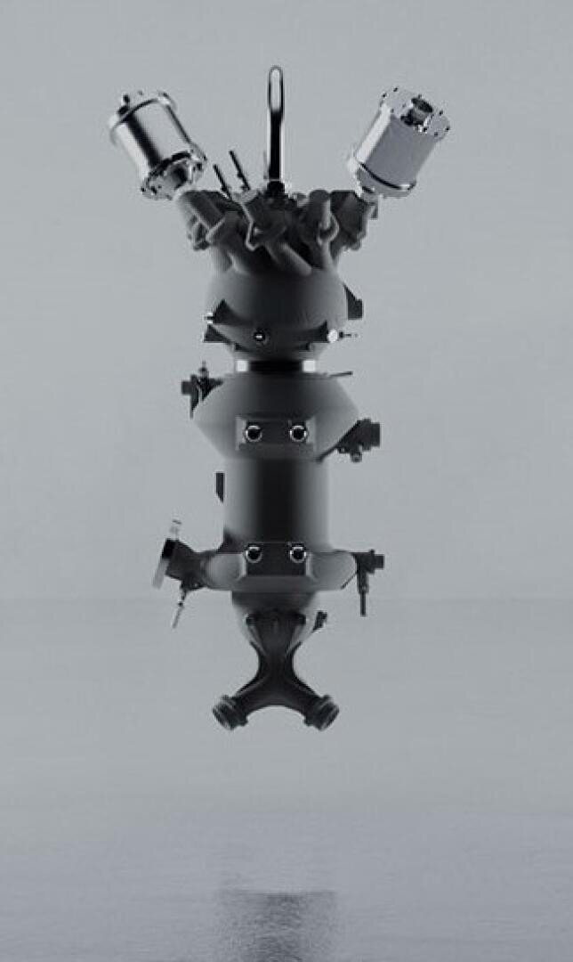Ein schlanker, metallischer Raketenmotor hängt vertikal vor einem schlichten grauen Hintergrund. Der Motor verfügt über mehrere Düsen, Bolzen und komplizierte mechanische Komponenten.